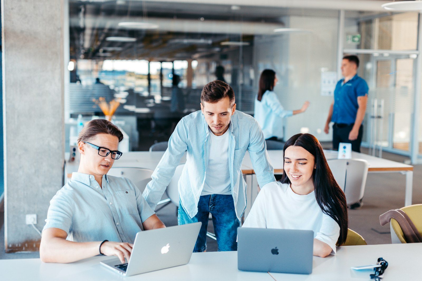 Team working together on laptops around a table in a bright office